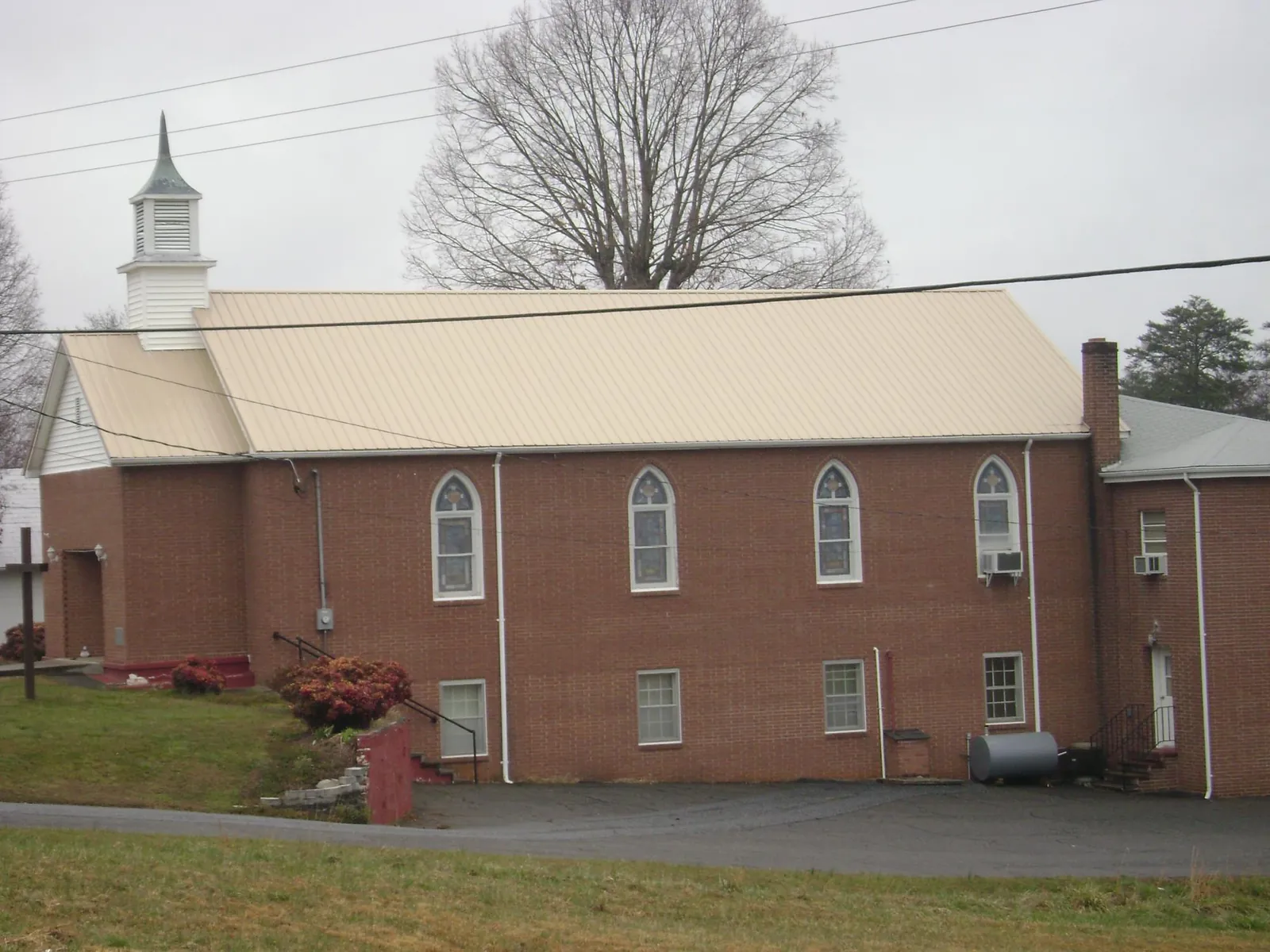 New tan metal roof on a brick church with a white steeple in Windsor